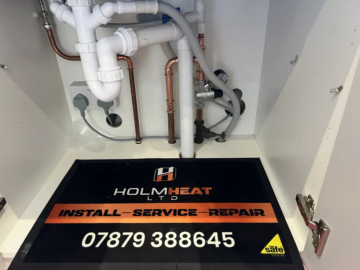 Neatly installed plumbing and valves below a kitchen sink